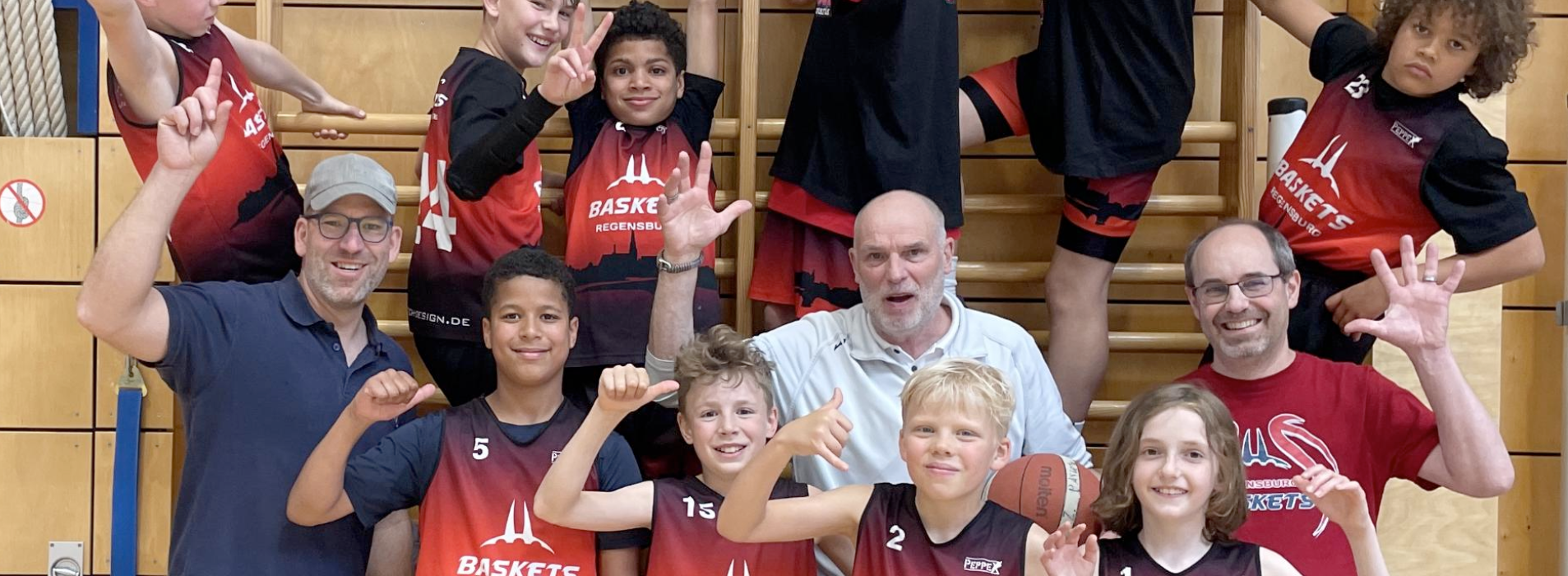 Jugend Basketballteam jubelt vor einer Sprossenwand