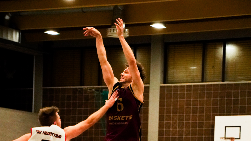 Oberkörper eines Basketballspielers am Ende der Wurfbewegung mit Verteidiger