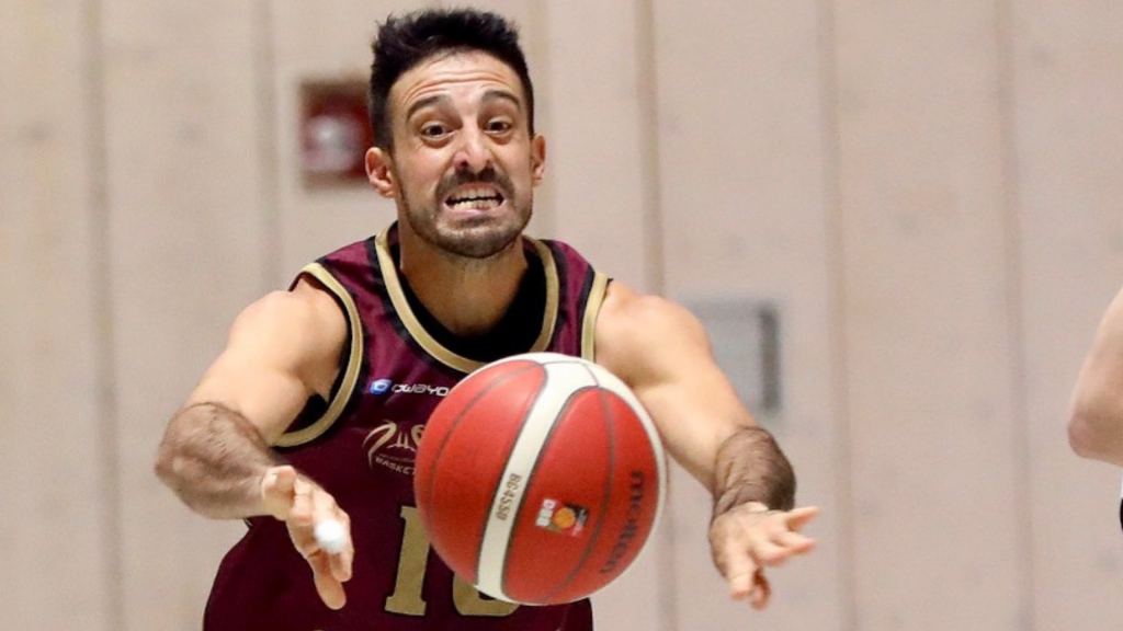 Santiago Rodriguez, Basketballspieler passt den Ball energisch mit angestrengtem Gesichtsausdruck